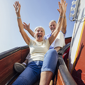 Happy male and female with hands in the air coming down a slide