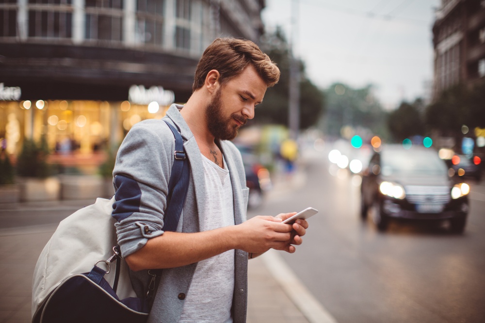 Man looking at his phone crossing the street