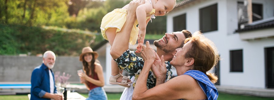 Family celebrating in backyard of home with happy baby