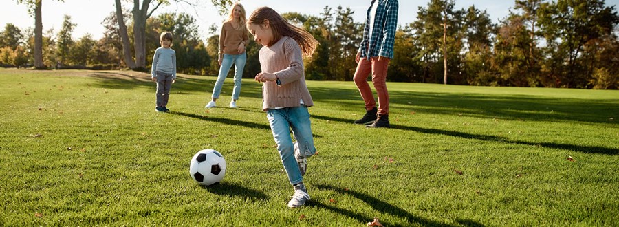 Family playing soccer in grass field