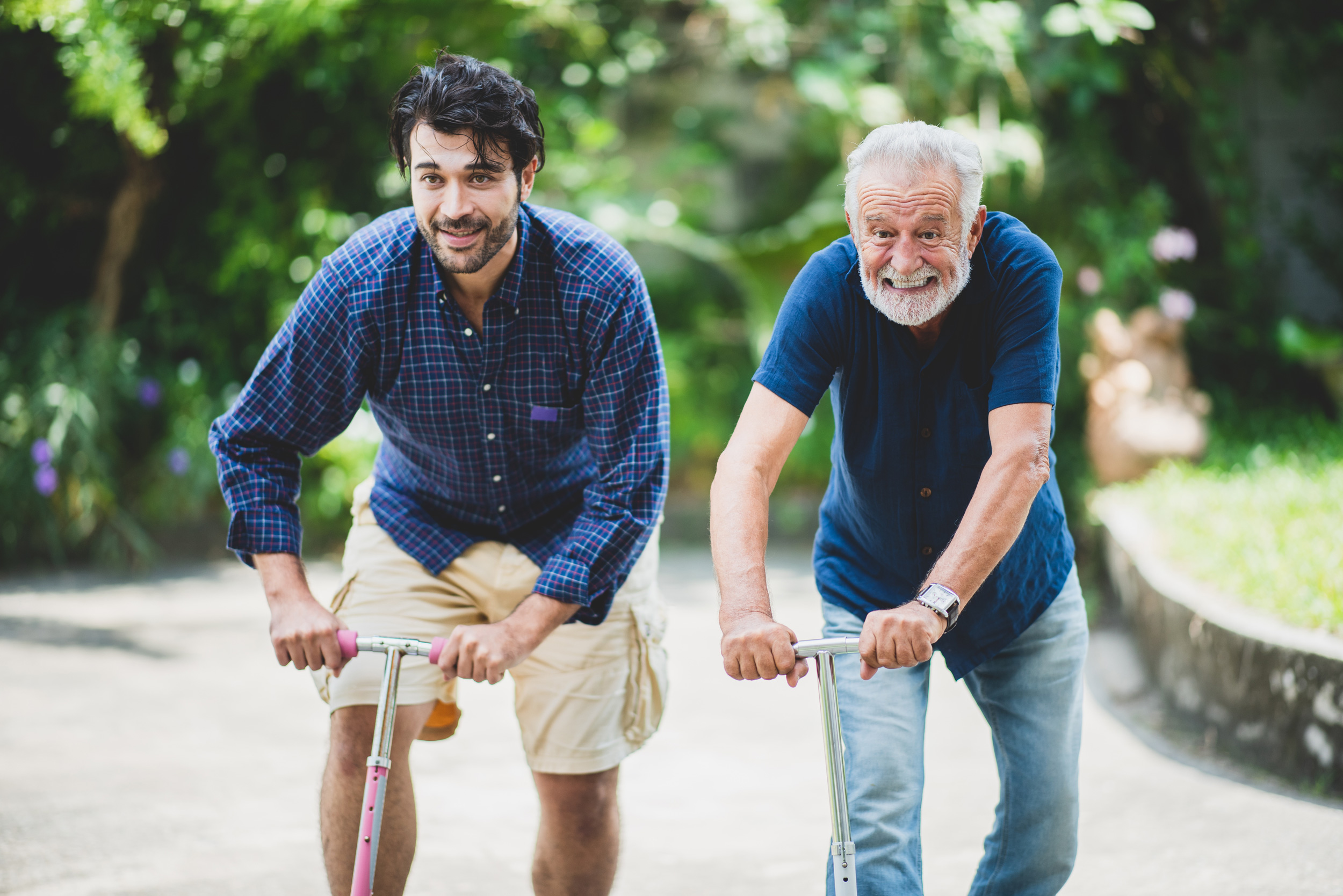 Father and son staying young riding scooters