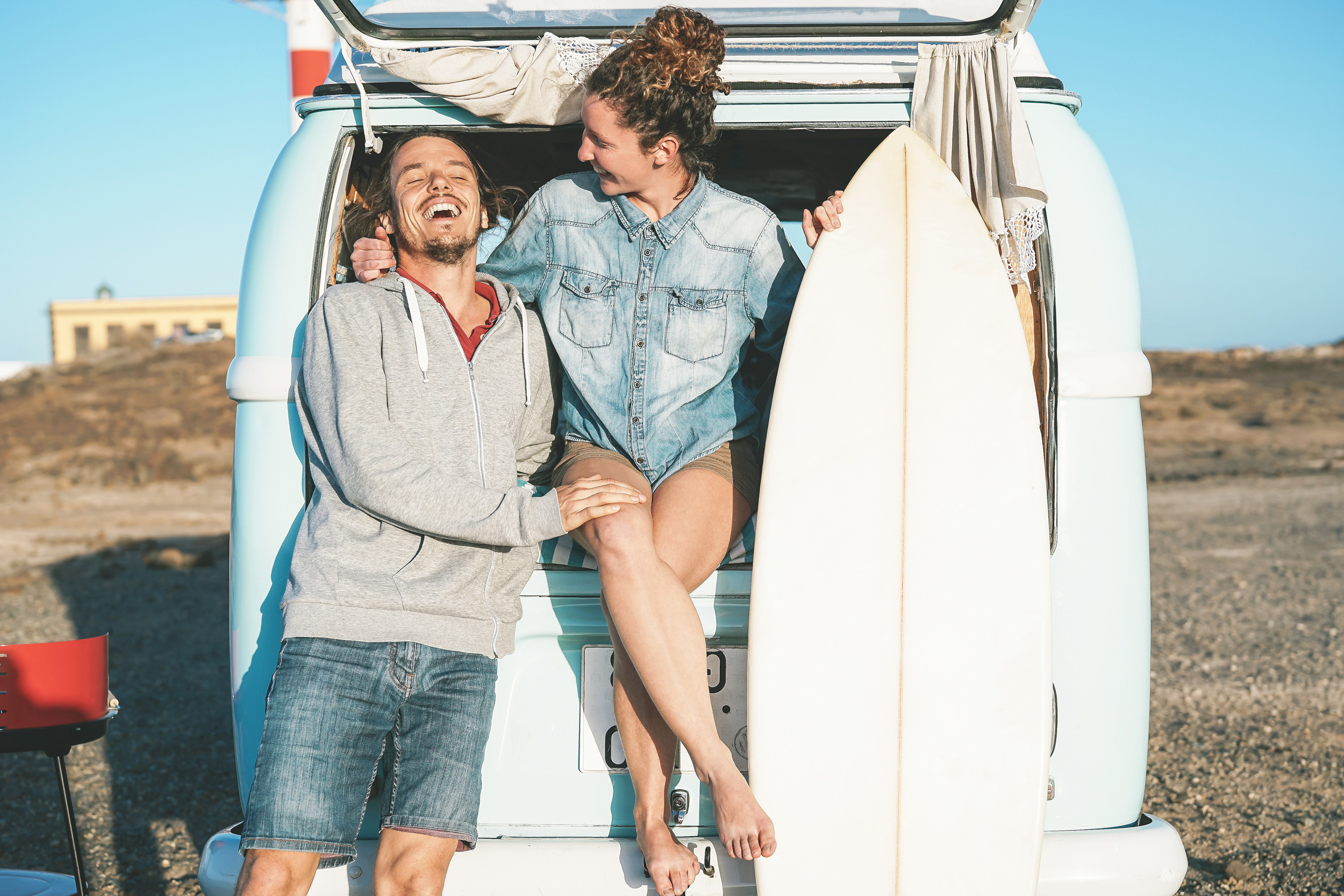 Surfing couple on holiday sitting in van