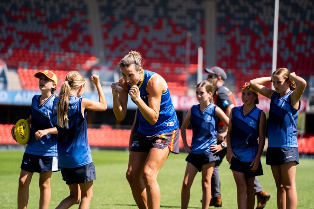Gold Coast SUNS AFLW player Clara Fitzpatrick with the Year 6 Marymount Primary girls AFL team